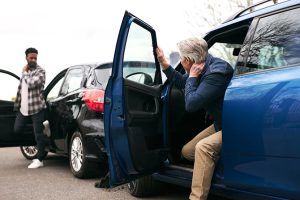 Insurance Insights: Auto Dealership Loss Trends Feature - Two cars in an accident and both male drivers are getting out of their cars holding their body as if injured.